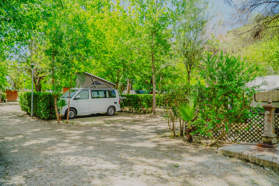 Piazzole ombreggiate dell'area camping con un camper parcheggiato tra gli alberi
