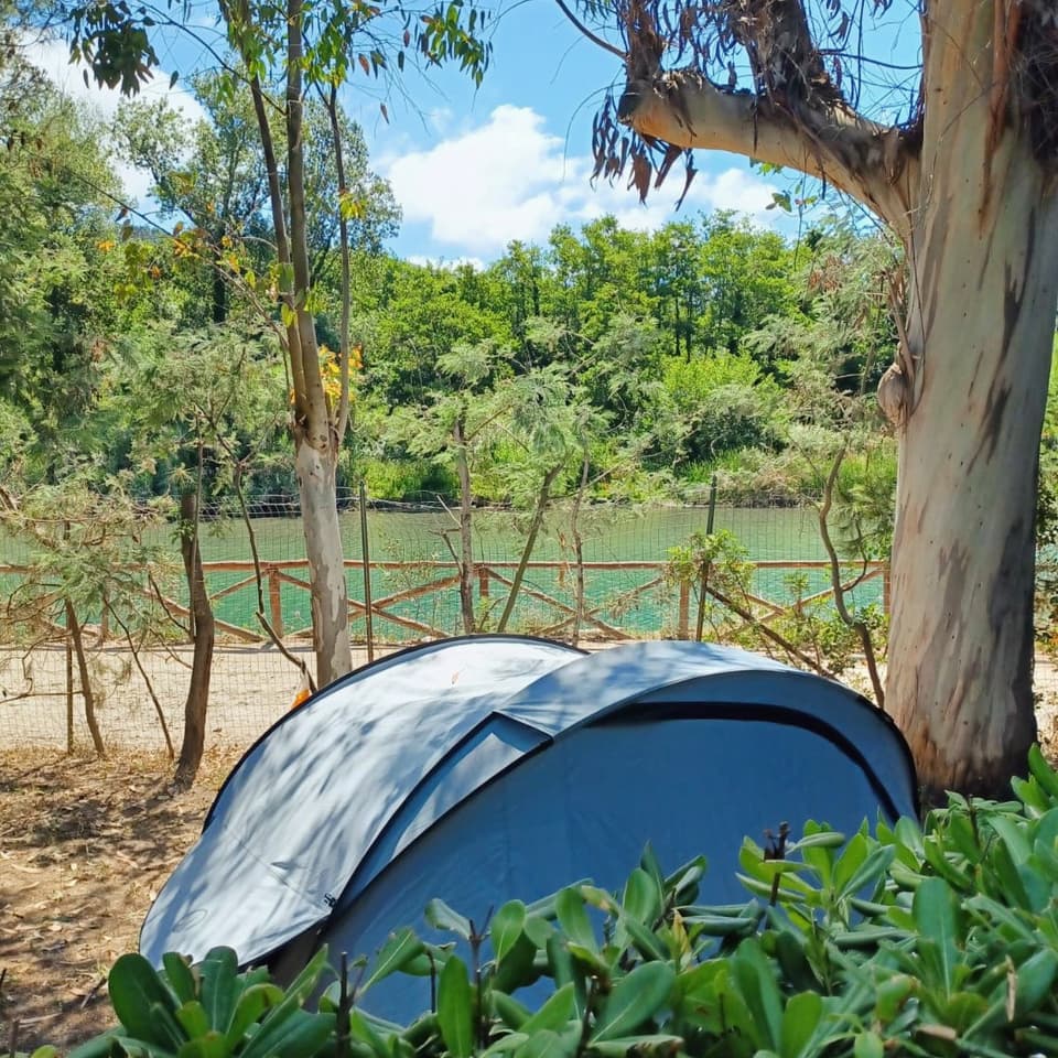 Una tenda montata all'ombra vicino al fiume